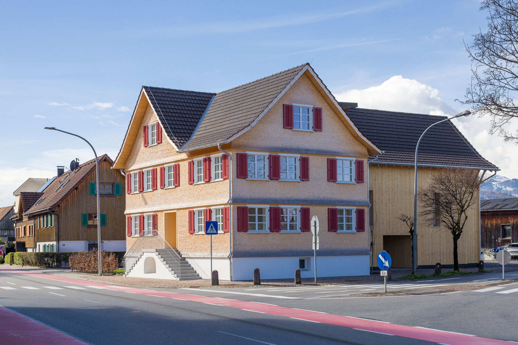 Saniertes Wohnhaus mit Schindelfassade und roten Fensterläden